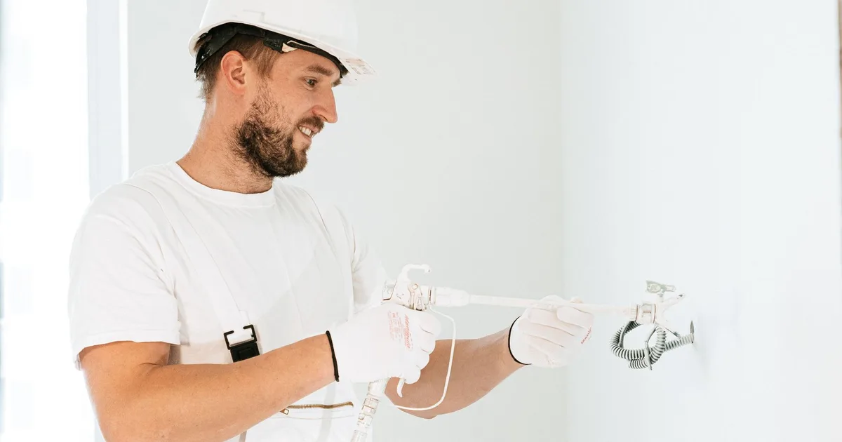 Elektriker mit Schutzhelm installiert Unterputzdose in Wand bei Elektrosanierung Altbau München