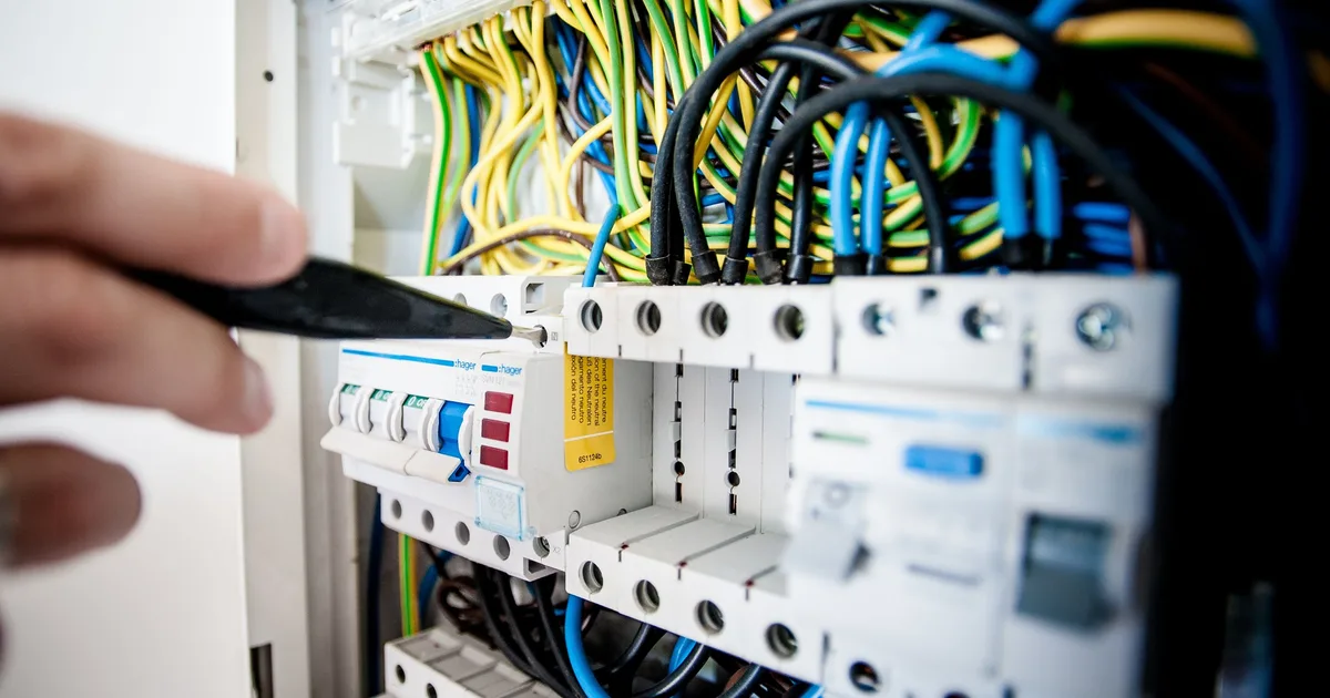 Hand mit Schraubendreher an einer Unterverteilung mit FI-Schutzschalter und Leitungsschutzschaltern, Ratgeber von Rucker Elektro München