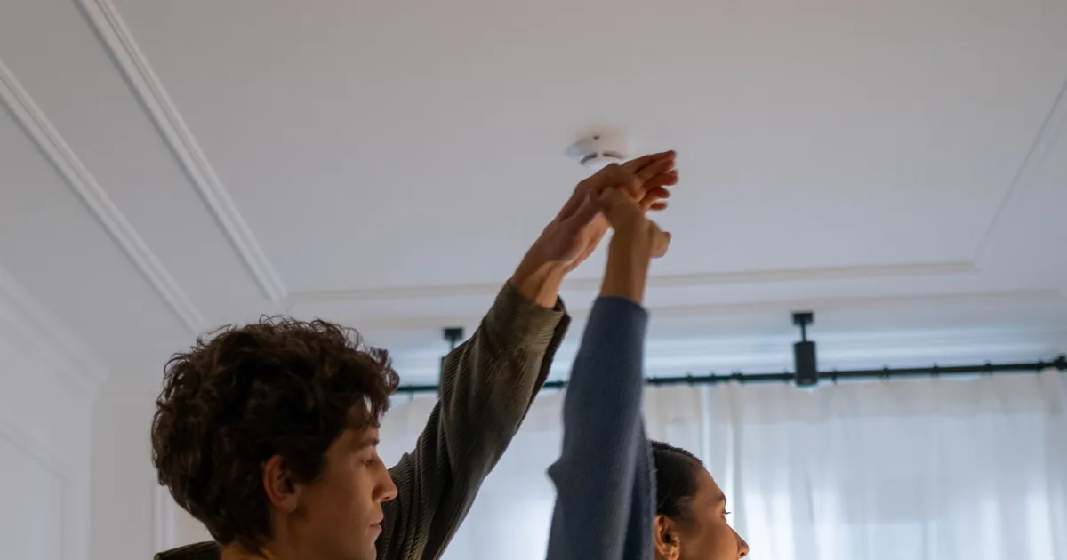 Rauchmelder an der Zimmerdecke einer Münchner Wohnung wird von Bewohnern geprüft, Ratgeber von Rucker Elektro München