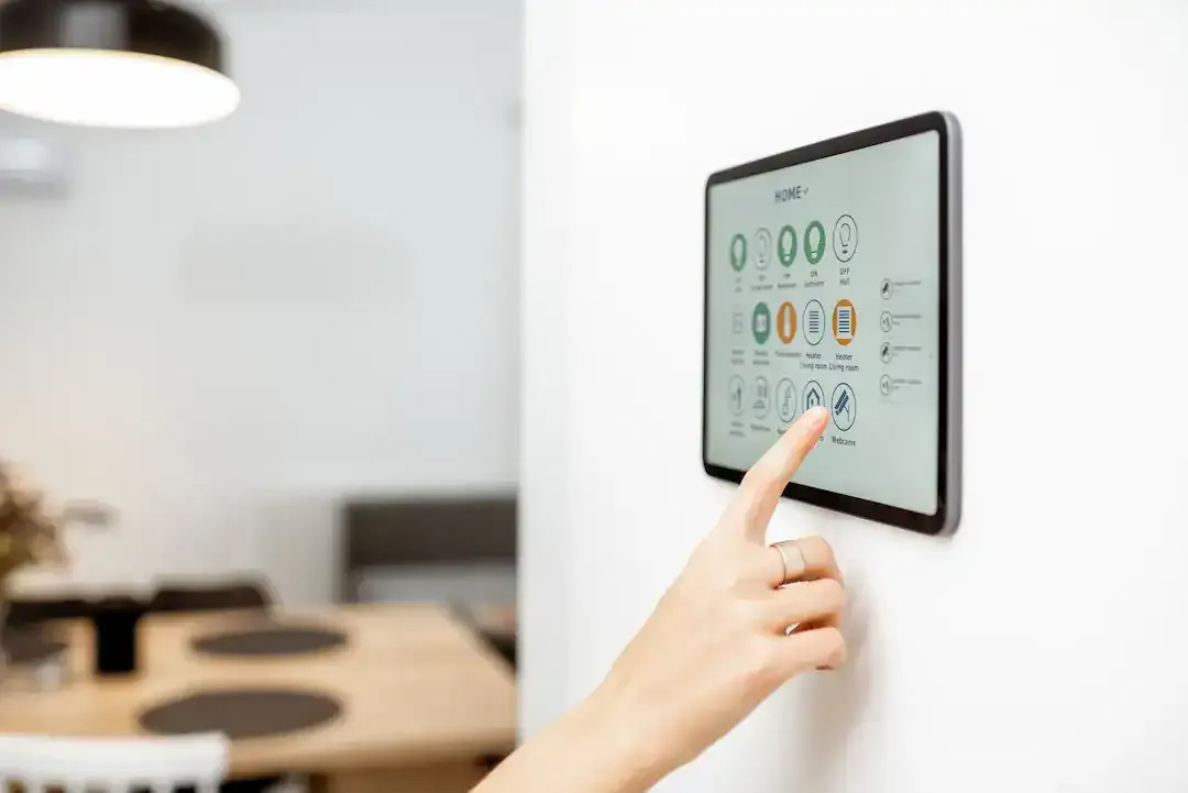 Person bedient ein wandmontiertes Smart-Home-Bedienpanel in der Wohnung, Ratgeber von Rucker Elektro München