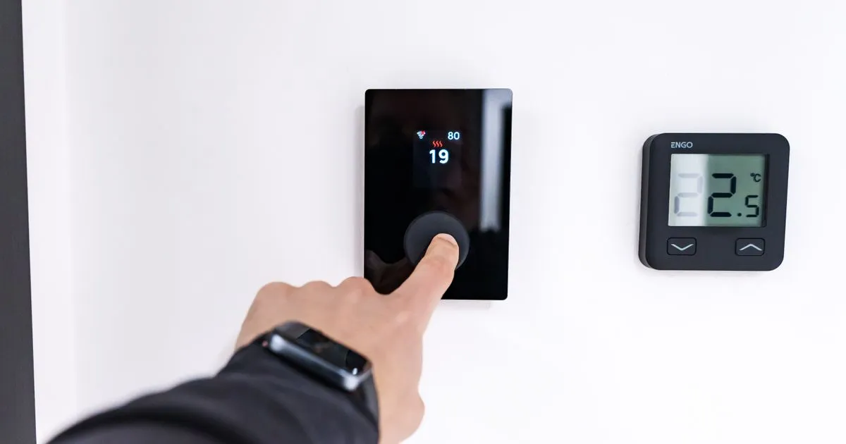 Hand bedient ein digitales Energiedisplay zur Verbrauchssteuerung im Smart Home