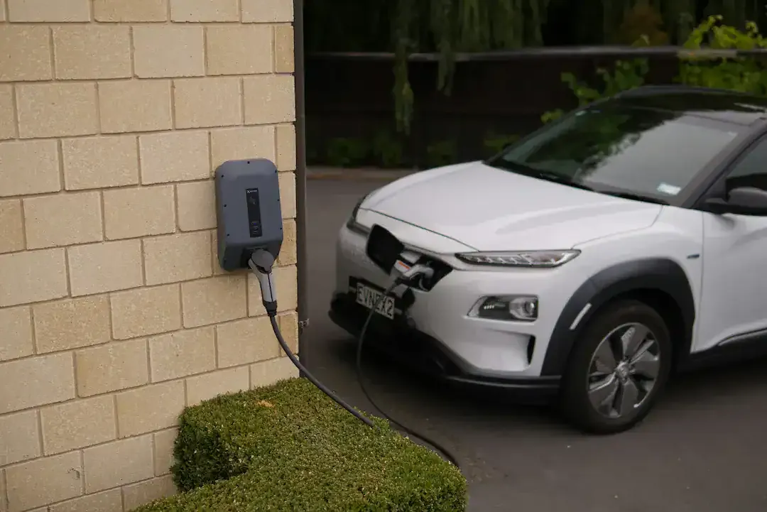 Weißes Elektroauto lädt an einer an der Hauswand montierten Wallbox, Ratgeber von Rucker Elektro München