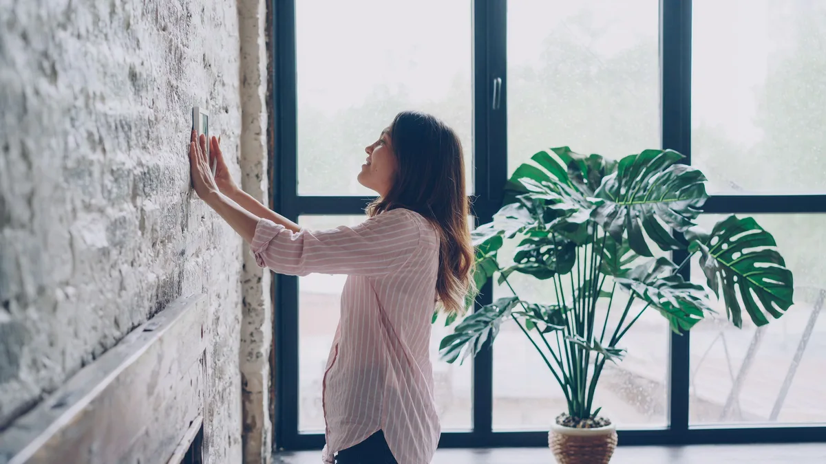 Bewohnerin bedient ein Smart-Home-Wandpanel im Wohnraum, wie es Rucker Elektro in München installiert