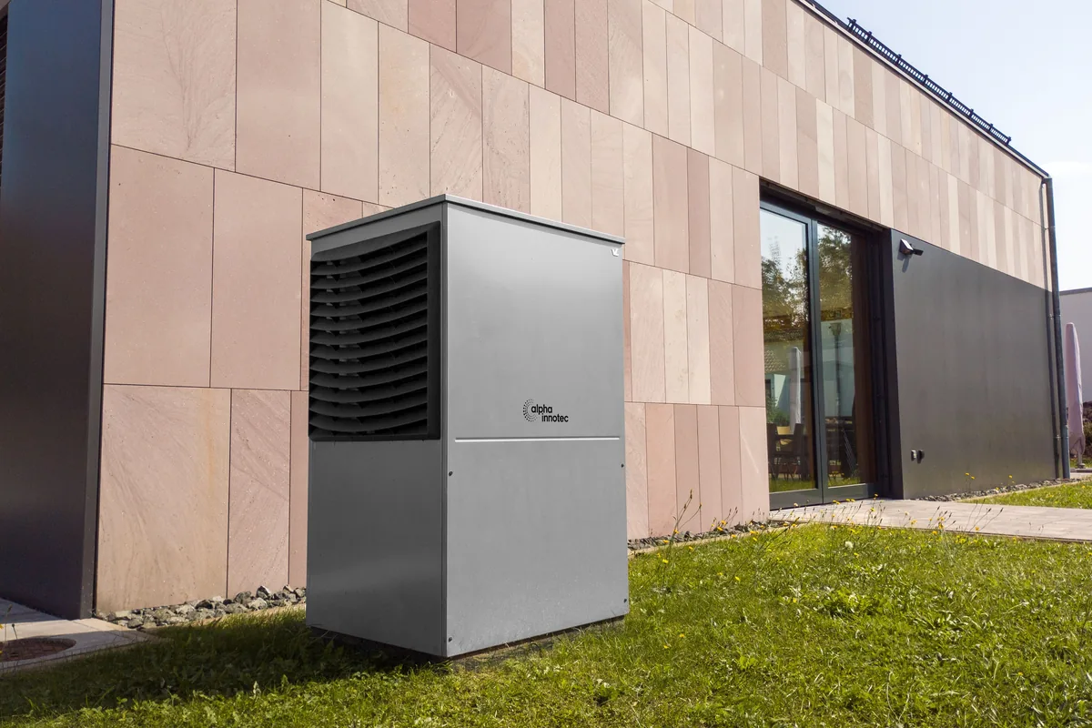 Wärmepumpen-Außeneinheit neben einem Wohnhaus im Grünen, Elektroanschluss für Wärmepumpen in Waldtrudering, Rucker Elektro München
