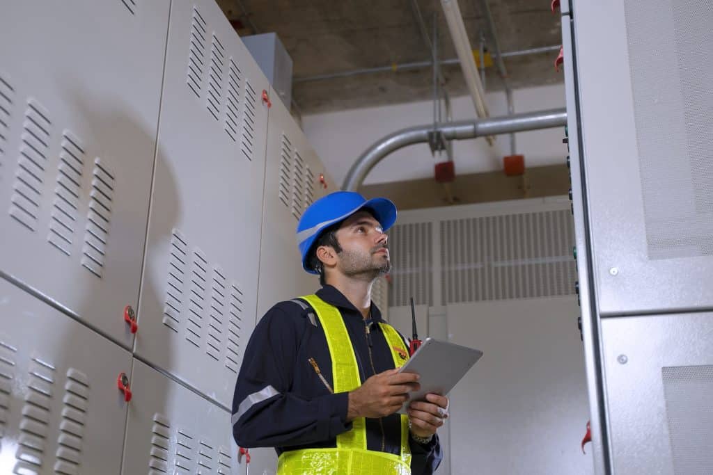 Servicetechniker überprüft elektrische Anlagen beim E-Check in München in einem Technikraum
