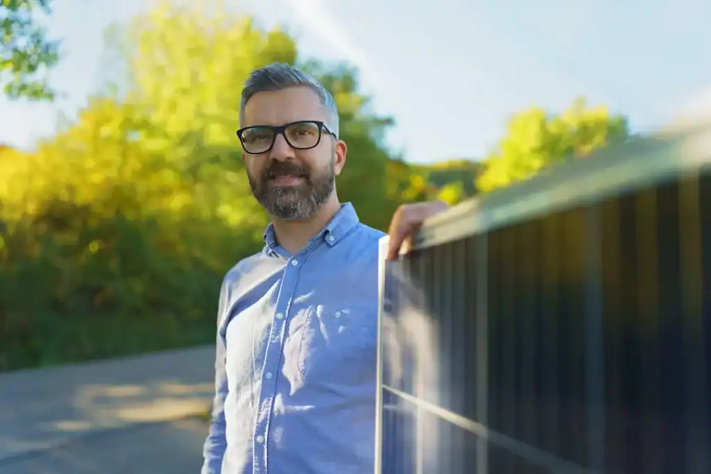 Mann steht neben einem Solarpanel im Freien.