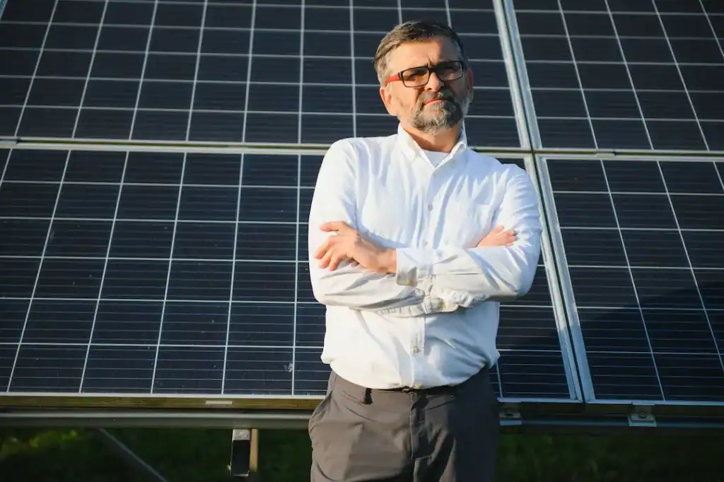 Mann mit Sonnenbrille vor Solarmodulen, nachhaltige Energie.