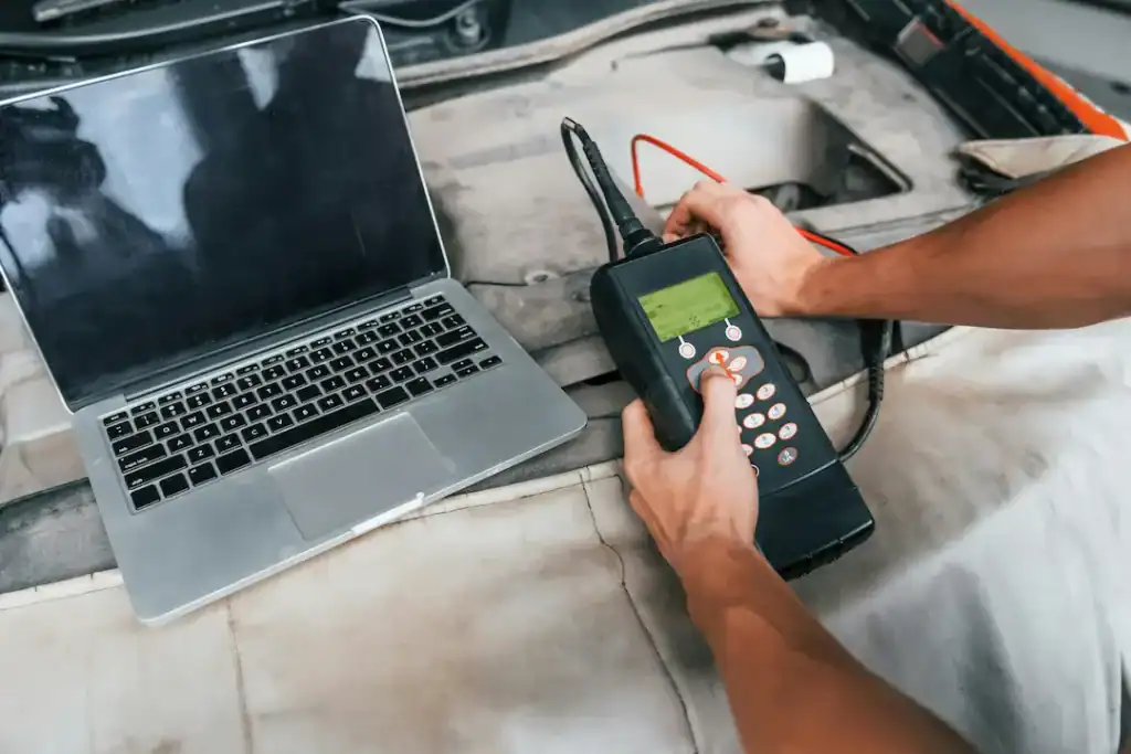 Diagnosegerät wird am Auto neben Laptop verwendet.