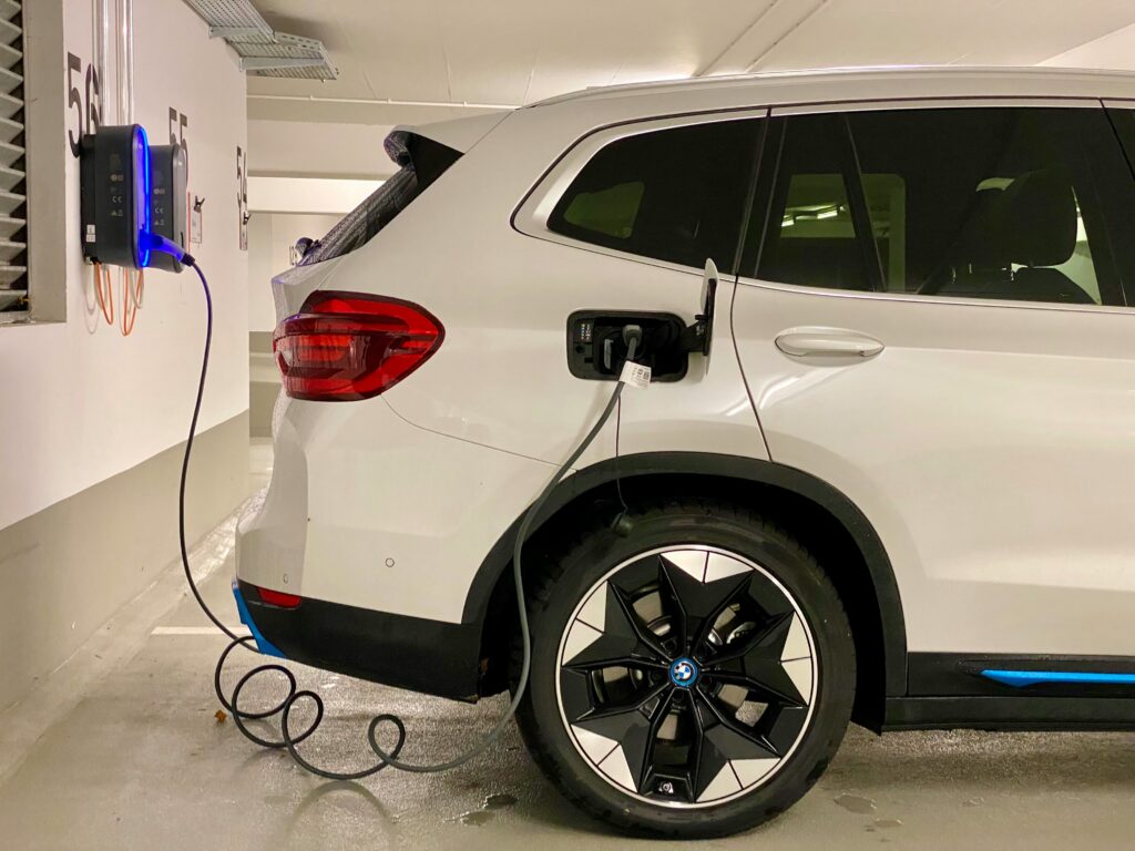 Weisser BMW iX3 wird an Wallbox in Tiefgarage geladen