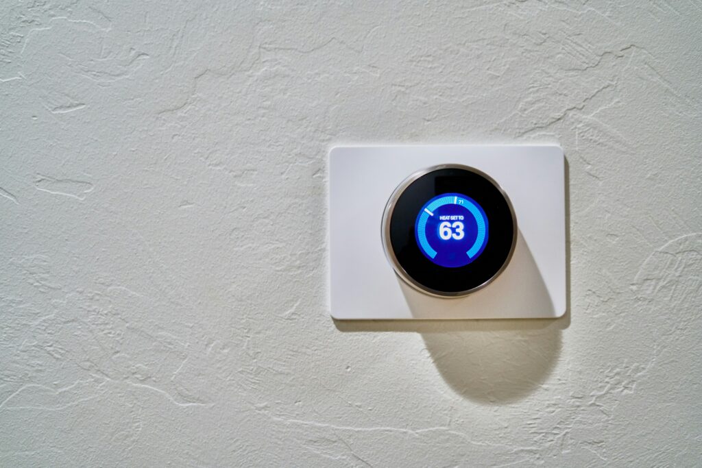 Google Nest Lernender Thermostat an weißer Wand zeigt Heizziel 63°F – Smart-Home-Klimasteuerung