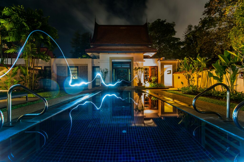 Modernes, beleuchtetes Haus mit Pool und Garten bei Nacht, Rucker Elektro.