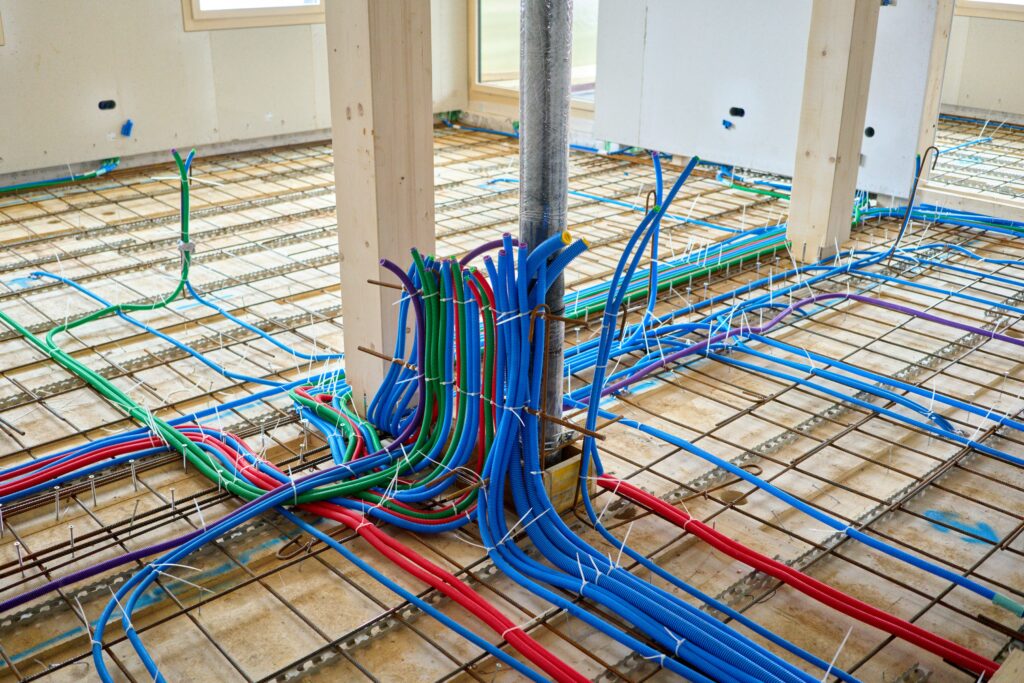 Farbige Leerrohre für Elektro- und Heizungsinstallation auf Bewehrungsgitter im Rohbau eines Neubaus
