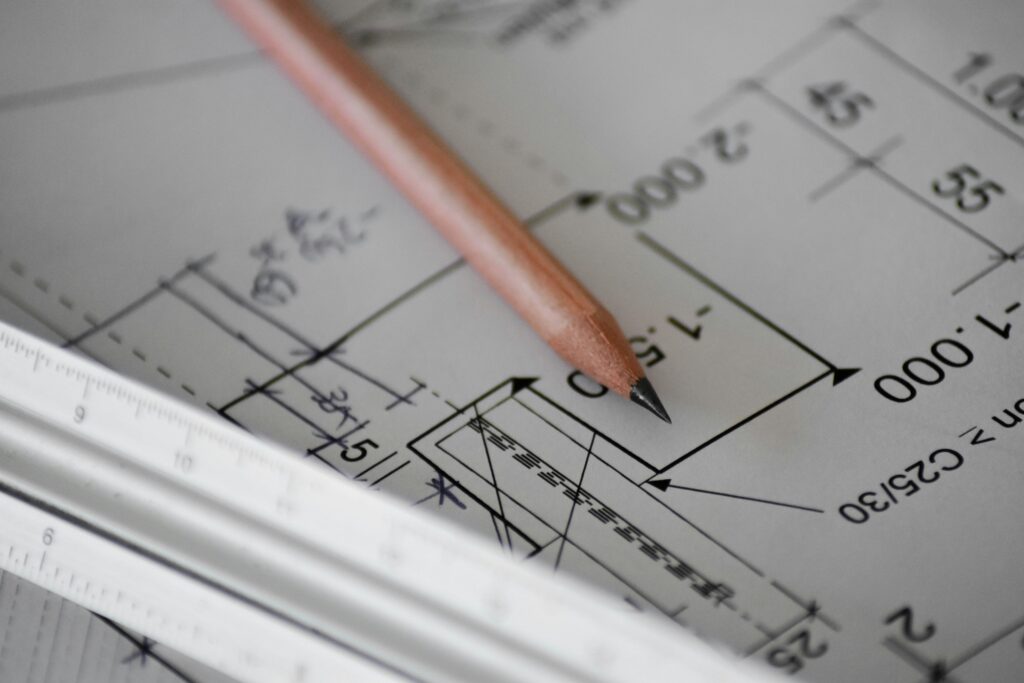 Bleistift und Lineal auf einem technischen Bauplan mit Maßangaben in der Nahaufnahme