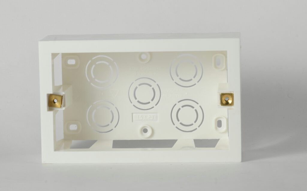 Leere weiße Aufputzdose für Elektroinstallation mit Kabeldurchführungen